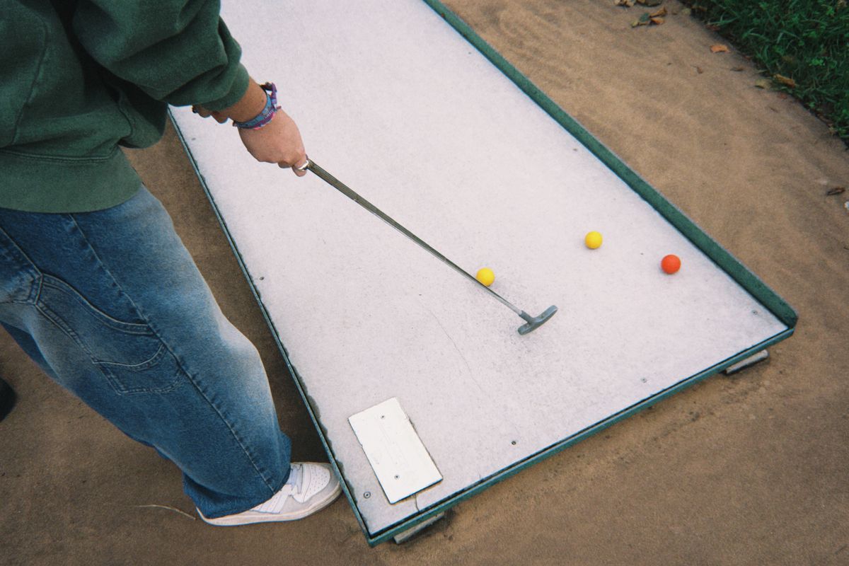Žogica in palica za mini golf na zeleni travi